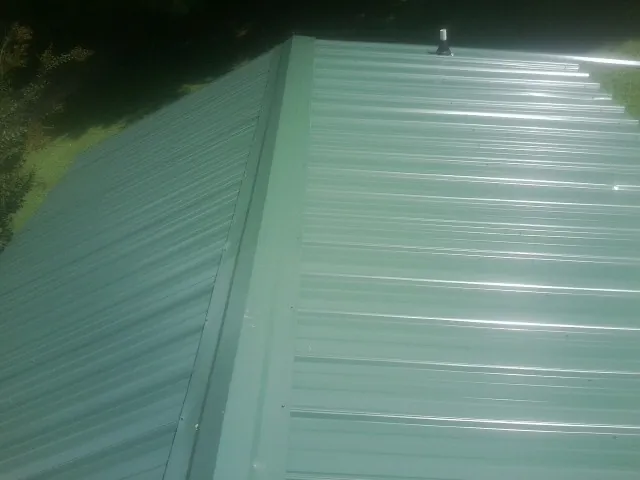 New green metal panels meeting at the ridge of a roof — Flat Roof Repair work by our crew in Milligan