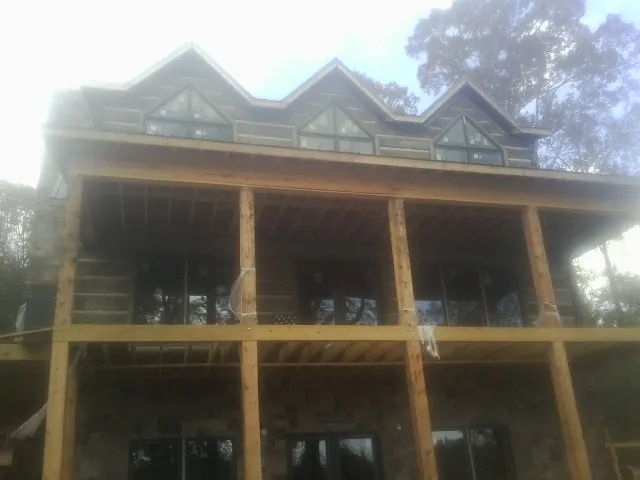 Dormers and porch framing on a large log home under construction — Roof Coating work by our crew in Milligan