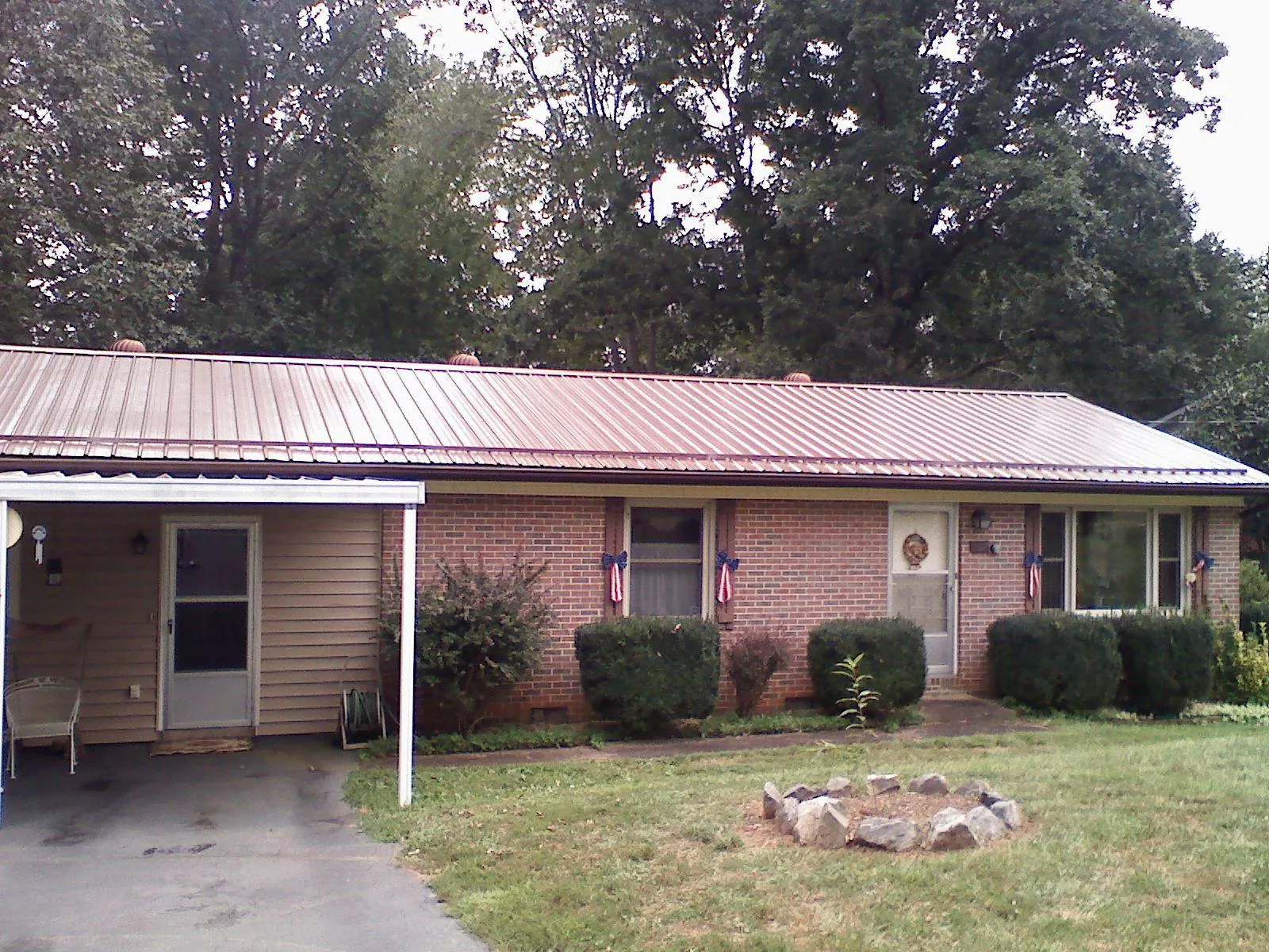 Bronze metal roof and carport on a brick ranch home — Roof Repair work by our crew in Milligan