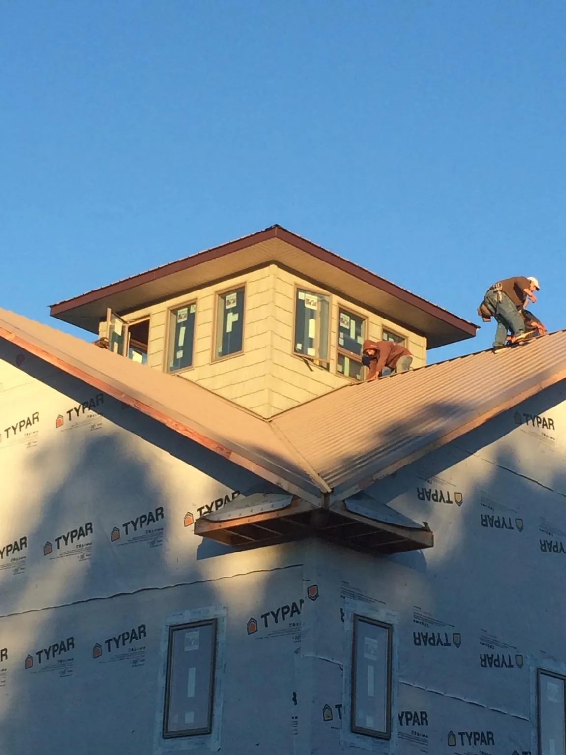 Roofers working around a rooftop cupola on a new metal roof at sunset — Roof Waterproofing in Milligan by Roofing Brothers